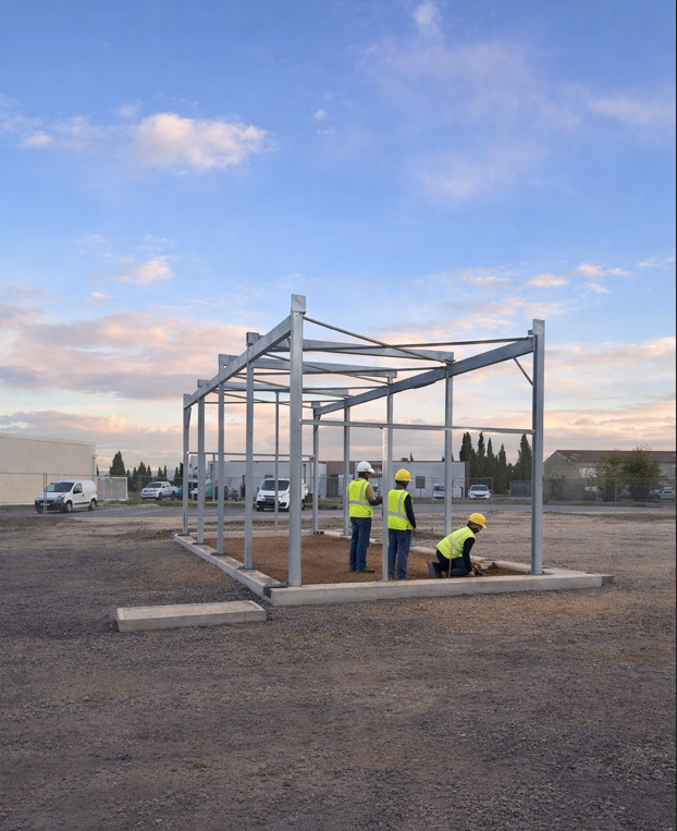 Équipe technique sous la structure métallique du futur centre de lavage auto à Laroque-des-Albères, un projet écoresponsable et photovoltaïque.